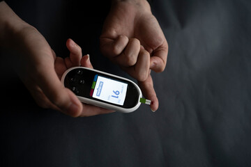 Caucasian young woman using digital glucometer at home.