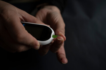 Woman using glucometer, checking blood sugar level.