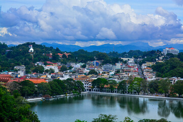 Blue sky with white clouds, a village with lake, a city with reservoir, a lake surrounded by green trees and buildings