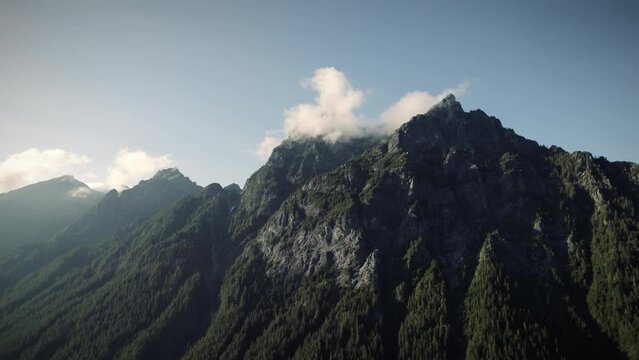 Dramatic Aerial of Rocky Mountain Ridge with Jagged Cliffs and fog Cloud Above Trees