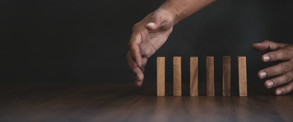 Close-up hand prevent wooden block falling domino concepts of financial risk management and...