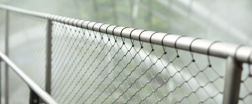 Silver metal fence with chain link in a tropical garden with a blur background. - Powered by Adobe