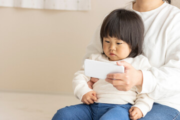 スマートフォン見る赤ちゃん（1歳8か月、女の子、日本人）と、見せる母親の手（30代、日本人）