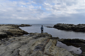 海の岩に立つ男性