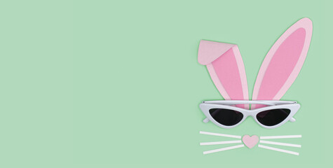 Banner. Happy easter greeting card. Bunny rabbit face made of pink paper with sunglasses on blue background. Creative easter minimal concept with copy space. Paper cut out art style. Paper Crafts