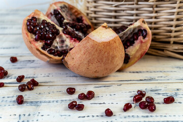 Pomegranates in a basket and on the table on a wooden background.