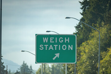 weigh station sign near green forest and road