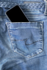 The upper part of old worn blue jeans and a smartphone with a black screen