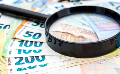 Magnifying glass on euro bills. Business and financial research.