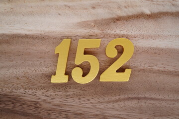 Golden Arabic numerals on real wood with brown and white pattern.