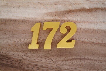 Golden Arabic numerals on real wood with brown and white pattern.