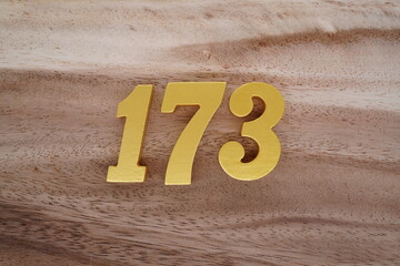 Golden Arabic numerals on real wood with brown and white pattern.