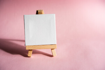 lectern, easel with white canvas, and space for message on a pink background