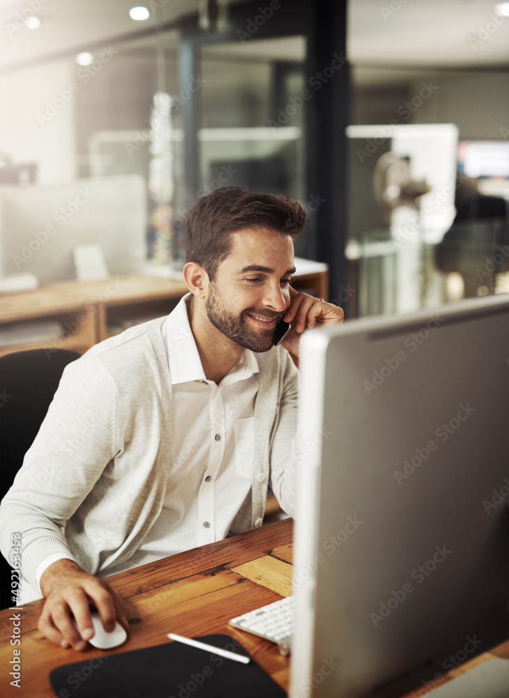 Poster Forwarding updates while working late. Shot of a handsome young businessman talking on a cellphone while working late in an office.