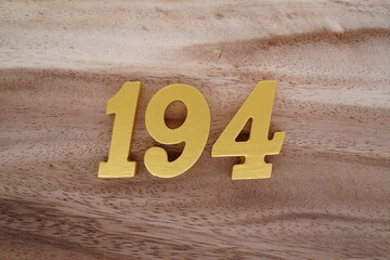 Golden Arabic numerals on real wood with brown and white pattern.