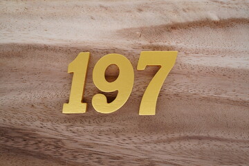 Golden Arabic numerals on real wood with brown and white pattern.