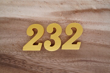 Golden Arabic numerals on real wood with brown and white pattern.