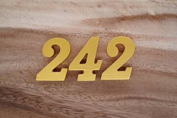 Golden Arabic numerals on real wood with brown and white pattern.