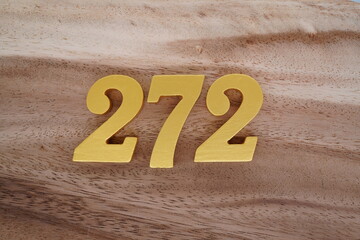 Golden Arabic numerals on real wood with brown and white pattern.