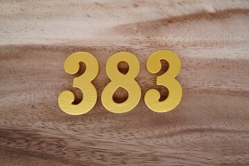Golden Arabic numerals on real wood with brown and white pattern.