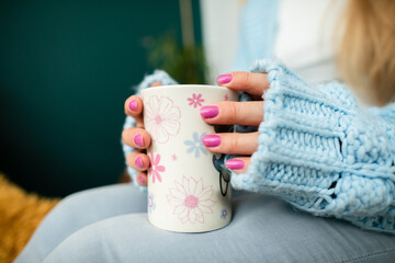 A woman's hands wrap around a mug of hot drink.