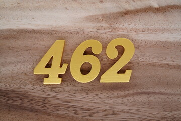 Golden Arabic numerals on real wood with brown and white pattern.