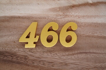 Golden Arabic numerals on real wood with brown and white pattern.