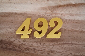 Golden Arabic numerals on real wood with brown and white pattern.