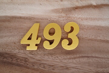 Golden Arabic numerals on real wood with brown and white pattern.