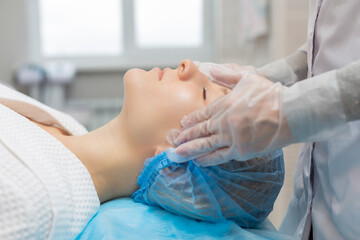 Side view of a girl relaxing on a couch during a facial massage in a beauty salon. Moisturizing and rejuvenation of the facial skin