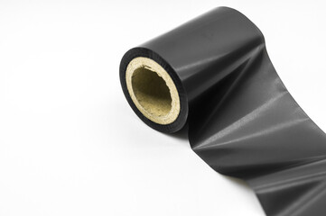 Black thermal transfer ribbon - TTR. Wax thermo ribbon on cardboard reel for barcode. Supply material for printing industry. Selective focus, isolated on white