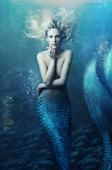 Shot of a mermaid swimming in solitude in the deep blue sea - ALL design on this image is created from scratch by Yuri Arcurs team of professionals for this particular photo shoot - obrazy, fototapety, plakaty