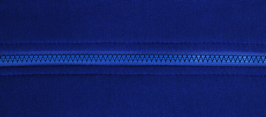 Close-up of a blue plastic zipper closed in the middle of a blue fabric texture