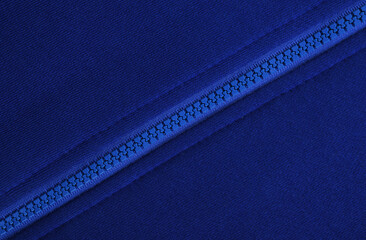 Close-up of a blue plastic zipper closed in the middle of a blue fabric texture