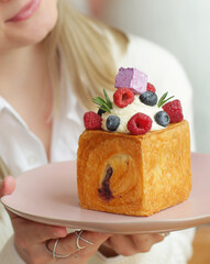 blond girl cube formed dessert with cream, raspberry, blueberry and marshmallow topping closeup...