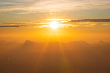 Mountains in clouds at sunrise in summer. Aerial view of mountain peak in fog. Beautiful landscape with high rocks, forest, sky. Top view from drone of mountain valley in low clouds. Foggy hills 