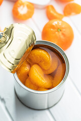 Canned tangerine. Pickled mandarin fruit in can on white table.