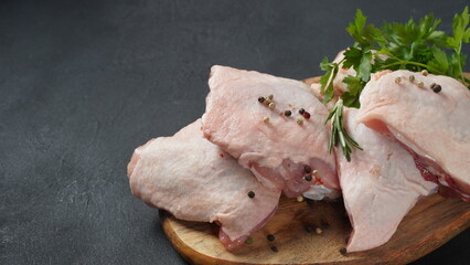 Raw chicken thigh on cutting board with spices.