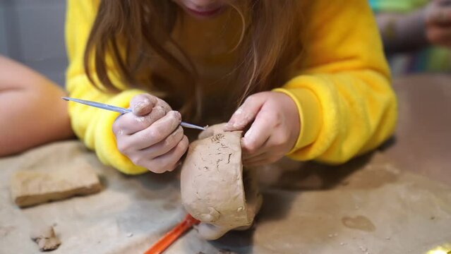 a hand of a little girl in yellow clothes sculpt from clay. developmental and creative activities with children. pottery workshop. a hobby for the whole family.