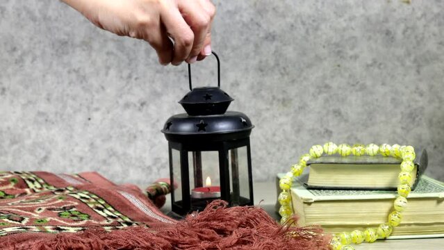 hand woman holding ornamental Arabic lantern, prayer mat and holy book with arabic calligraphy text mean Ramadan Mubarak. Translated: Happy and Holy Ramadan. Month of fasting for Muslims