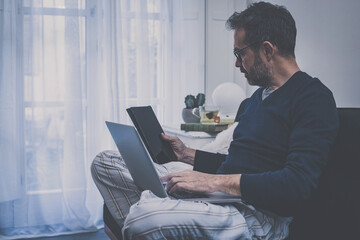 Man works with laptop sitting on the sofa. Male buying with credit card and electronic payment. Boy shopping online with computer, pad and smartphone. Internet lifestyle new marketing and shop concept