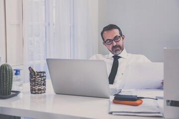 Business man working with laptop sitting at the desk. Male works at computer communicate online with remote office. Health care quarantine lifestyle, home working, homeschooling new technology concept