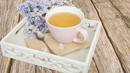 Beautiful white tray with a cup of tea and a branch of lilac