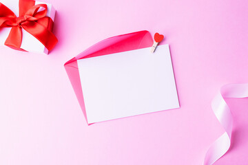 Mothers day gift. Spring white tulip flower, gift with red ribbon on flat lay pink background....