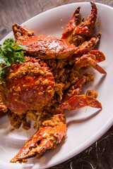 wok fried big fresh meat crab seafood in salted egg yolk paste sauce on wood table chinese banquet halal menu