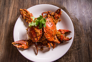 wok fried big fresh meat crab seafood in salted egg yolk paste sauce on wood table chinese banquet halal menu