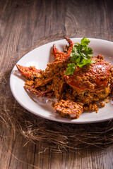 wok fried big fresh meat crab seafood in salted egg yolk paste sauce on wood table chinese banquet halal menu