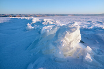 Ice hummocks on Baikal Lake in a sunny day. Winter landscape with beautiful transparent ice floes on foreground.