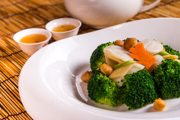 stir fried vegetable broccoli and asparagus with scallop in soy sauce on bamboo background chinese...