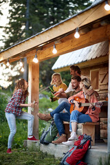 Young people on a beautiful cottage playing on a guitar and drinking beer